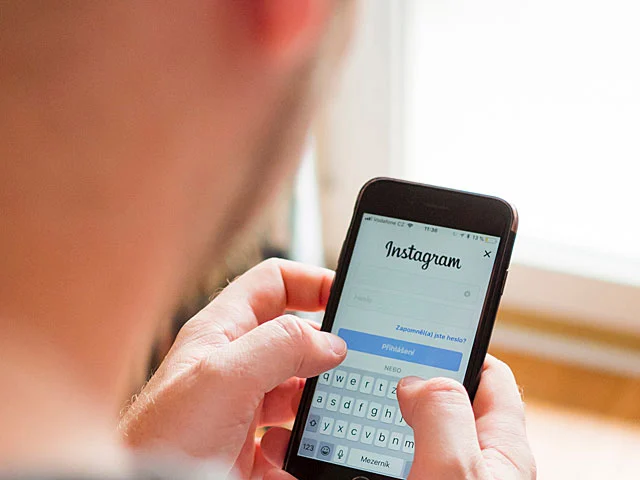 Person holding a smartphone open on the Instagram login screen, showing how hotels can use social media to win bookings