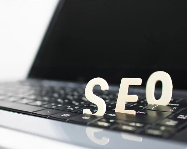 Wooden letters spelling SEO standing on a laptop keyboard, illustrating how responsive design helps hotel search rankings