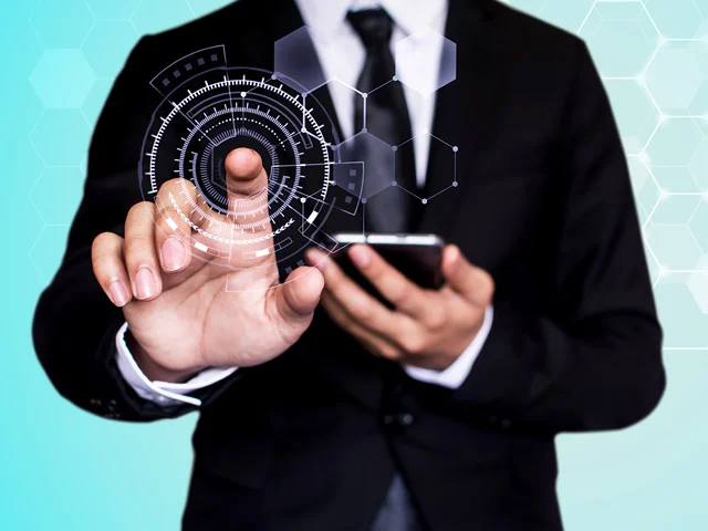 Businessman holding a smartphone and touching a digital dial with hexagon icons, representing a hotel channel manager