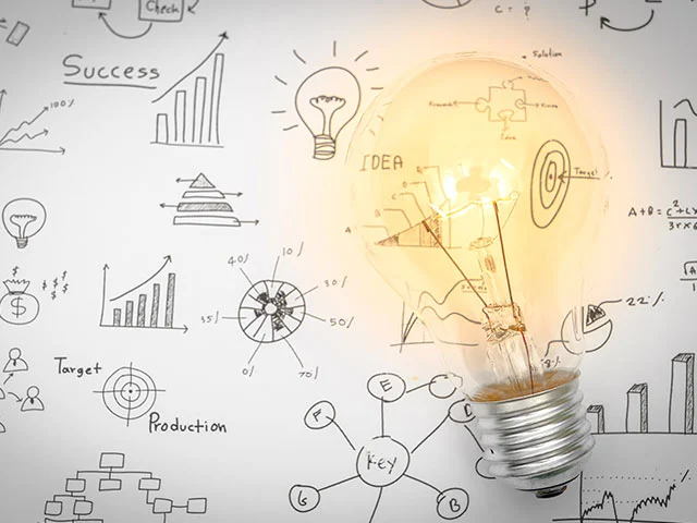 Glowing light bulb over hand-drawn graphs, targets and an Idea note, suggesting ideas for a hotel website that books more