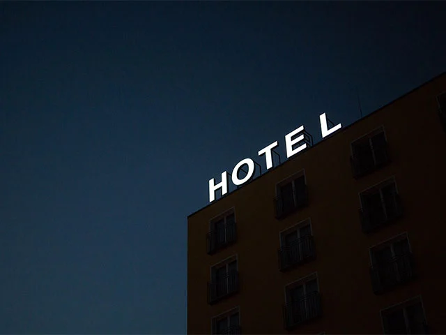 Illuminated HOTEL sign on top of a building against a dark night sky, representing hotel online distribution