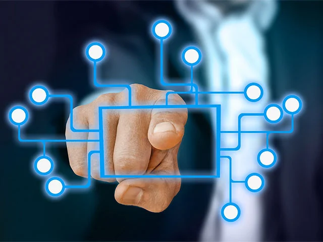 Businessman pointing at a glowing blue network diagram linked to many nodes, like a channel manager connecting sites