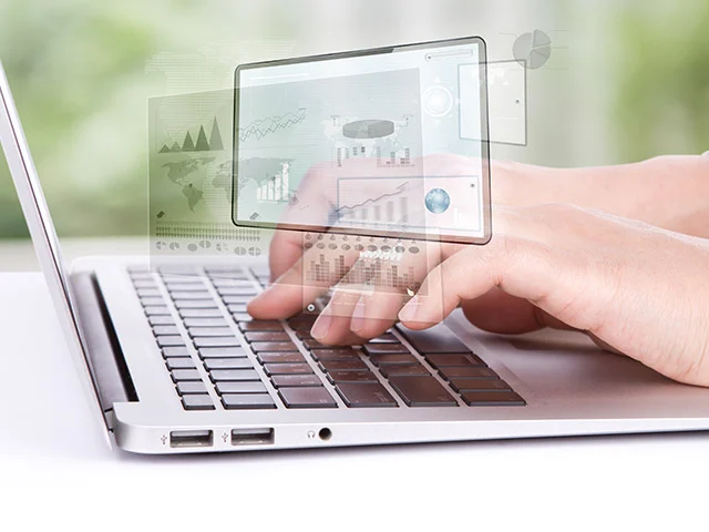 Hands typing on a laptop with floating transparent screens of charts and graphs, representing hotel website content