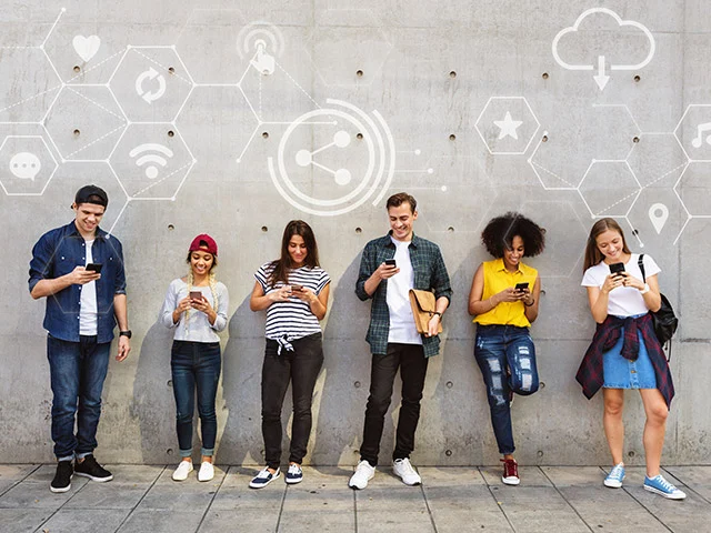 Six young people leaning on a concrete wall using smartphones under social media and Wi-Fi icons, showing mobile travel