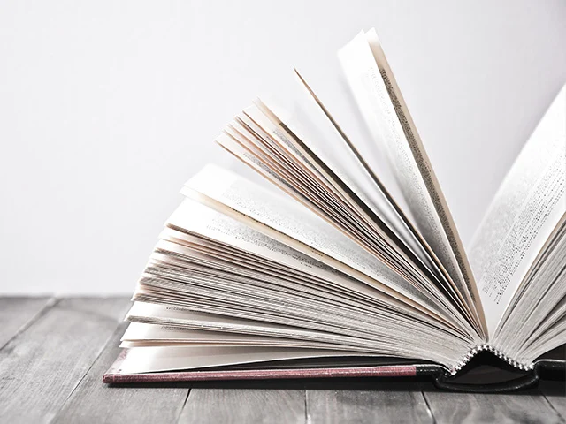 Open book with fanned pages on a grey wooden table, evoking storytelling in hotel marketing