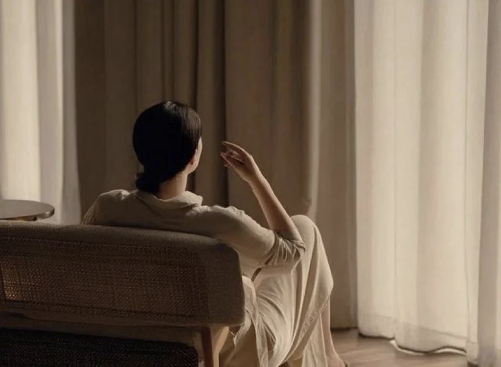 Guest relaxing in an armchair by curtained windows